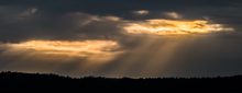 Ein paar Sonnenstrahlen am dunkelgrauen Himmel